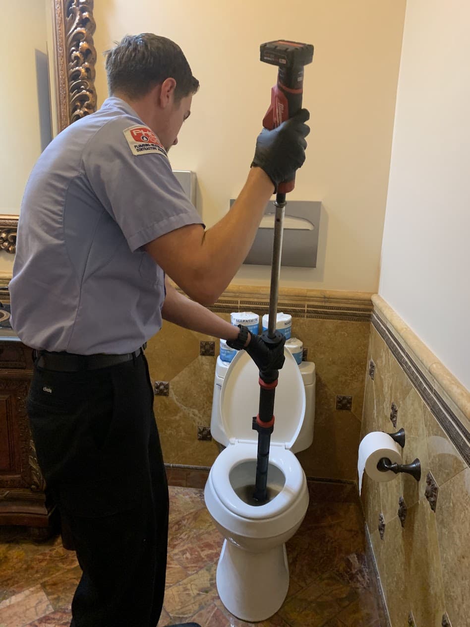 A professional performing a toilet plumbing service